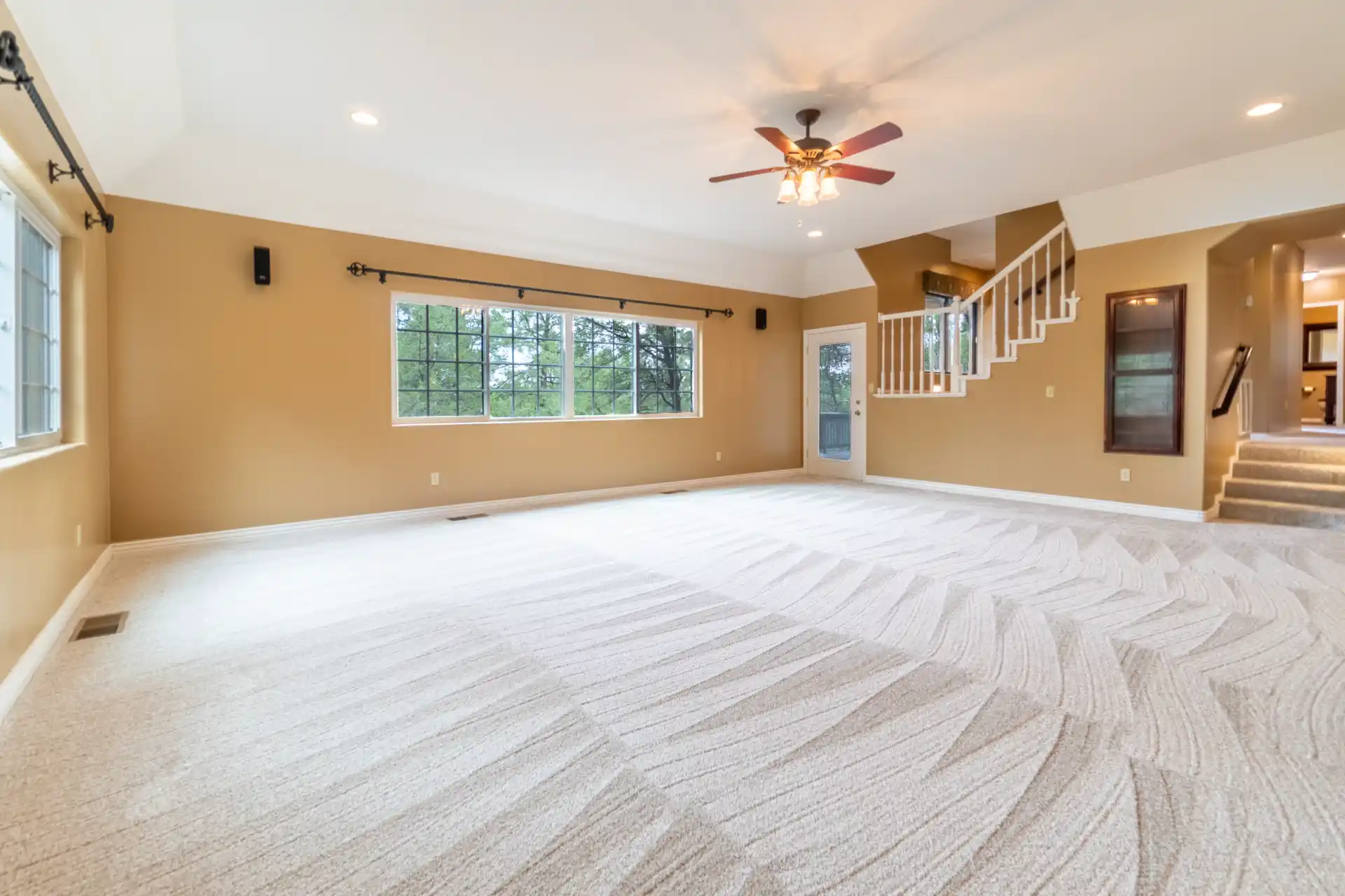 An empty room with a large window and a staircase leading up to a loft area