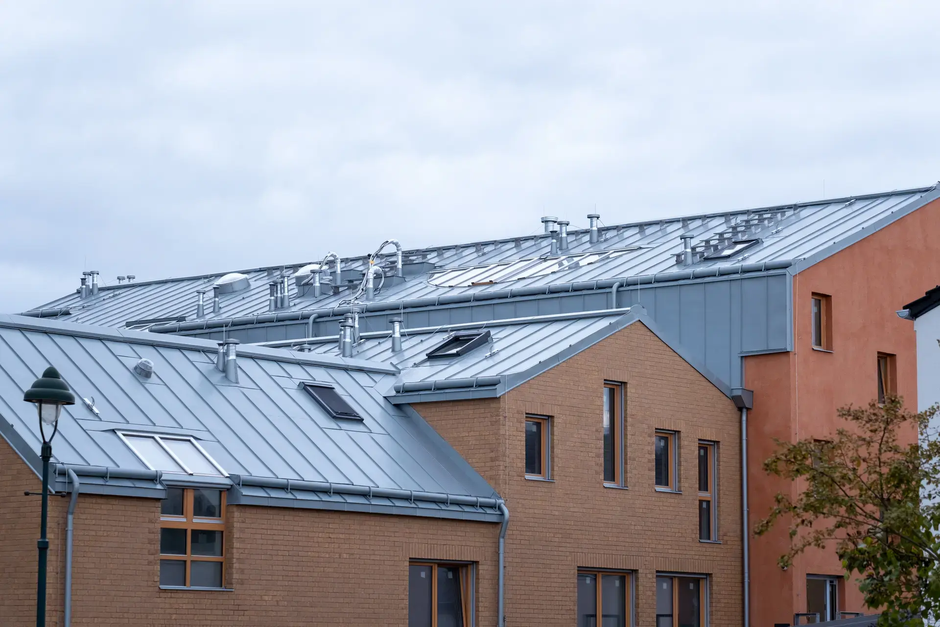 A large building with a metal roof and multiple windows under an overcast sky