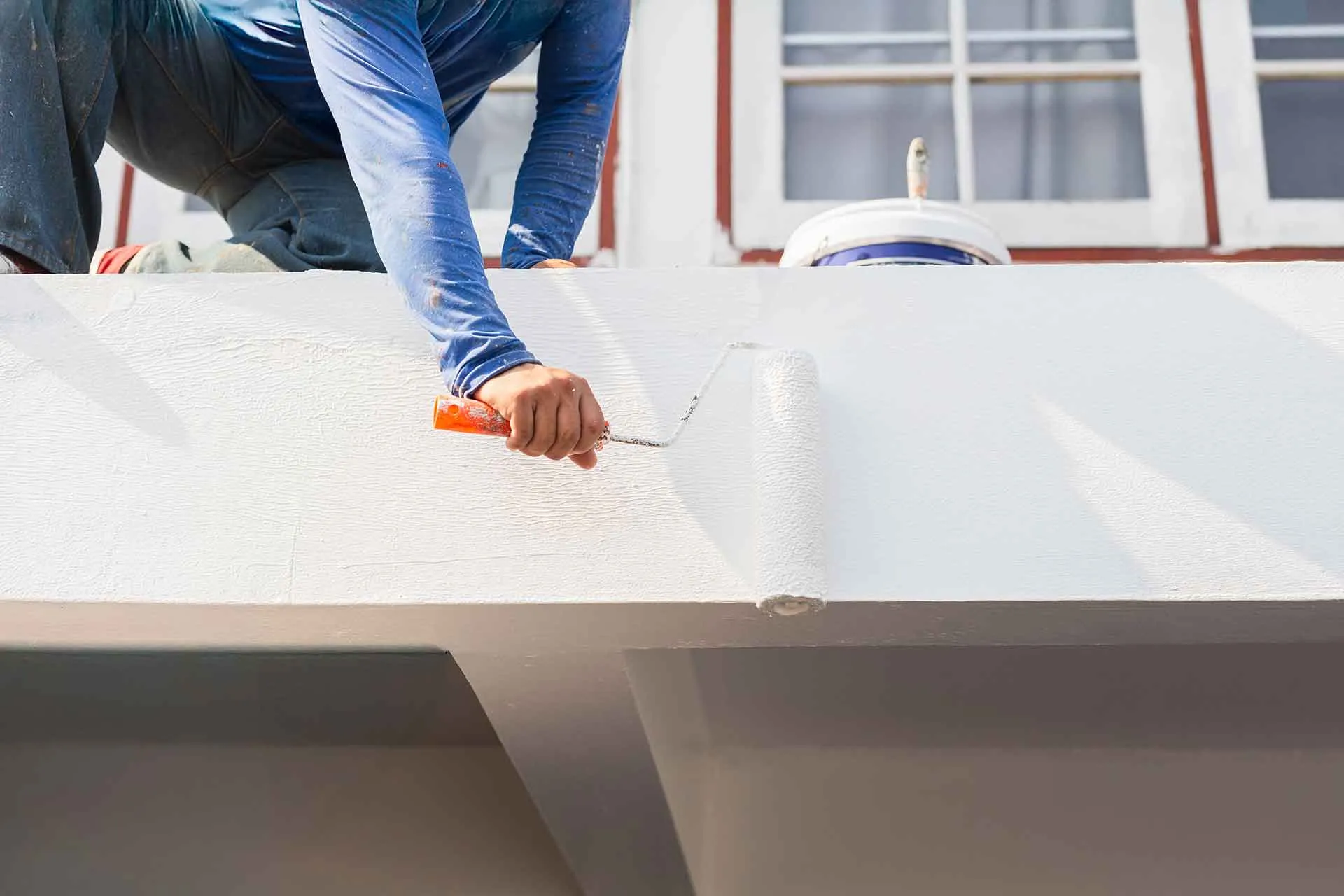 A person in blue jeans and a long-sleeved shirt working on a white roof