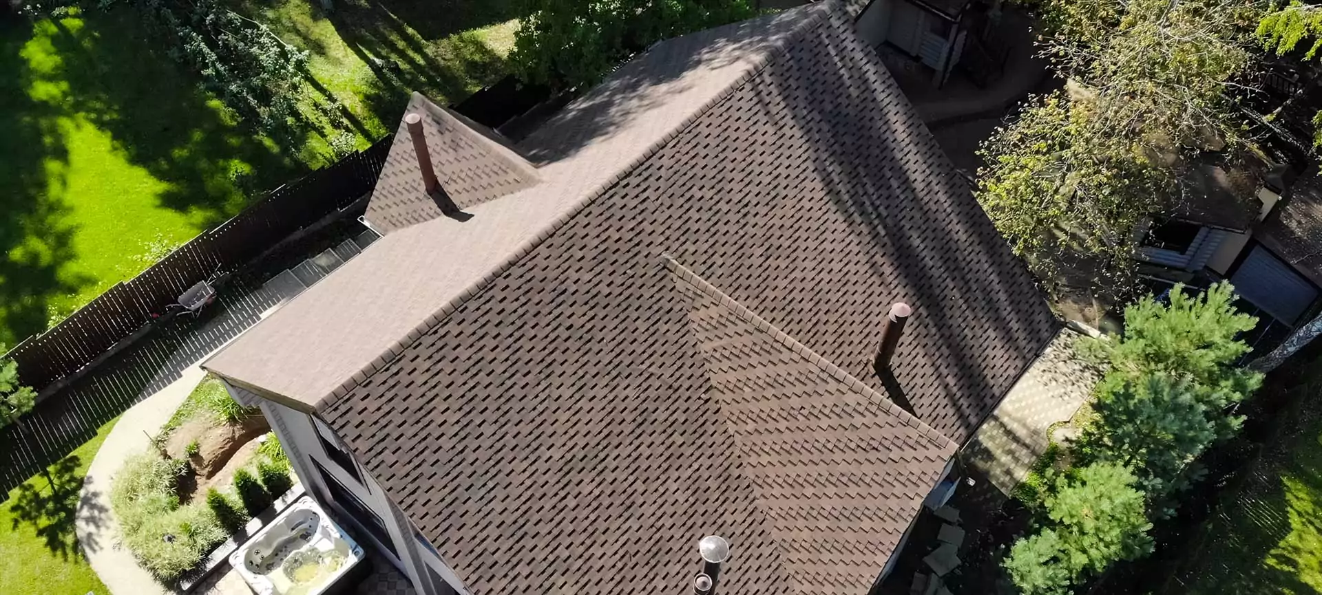 Aerial view of a roof with a brown shingle pattern and a chimney